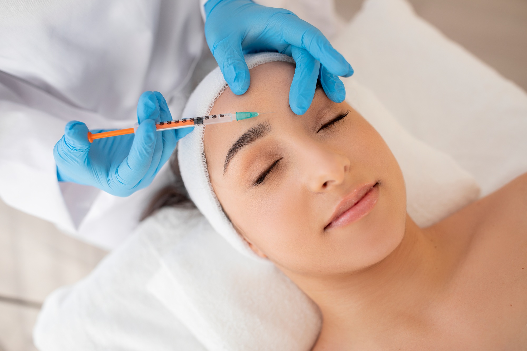 Aesthetic Treatment. Young beautiful woman getting injection on forehead in salon, closeup